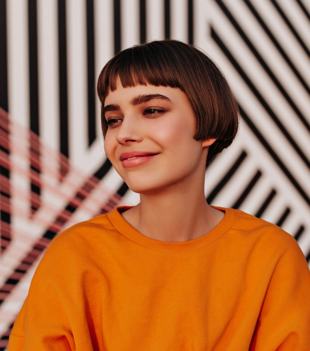 Woman with a bowl cut haircut with long sides.