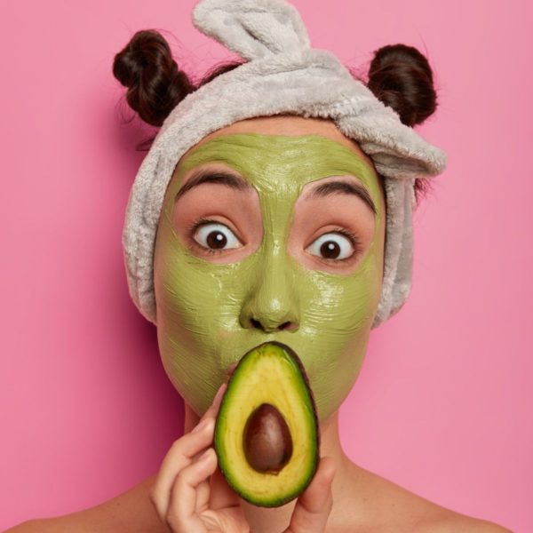 Beautiful woman with avocado face mask on