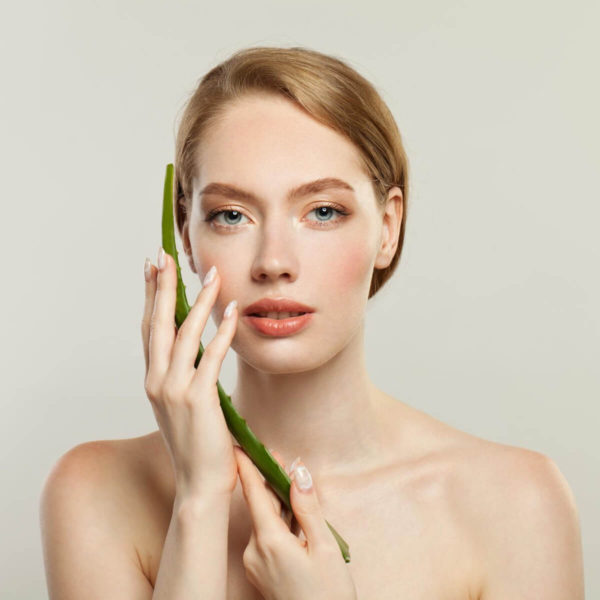 Woman holding aloe vera leaf for under-eye wrinkles treatment.