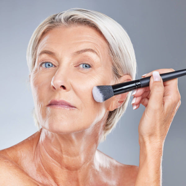 Woman applying foundation on mature skin.