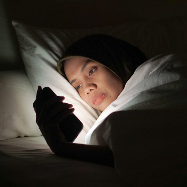Woman checking her phone with sleeping problems.